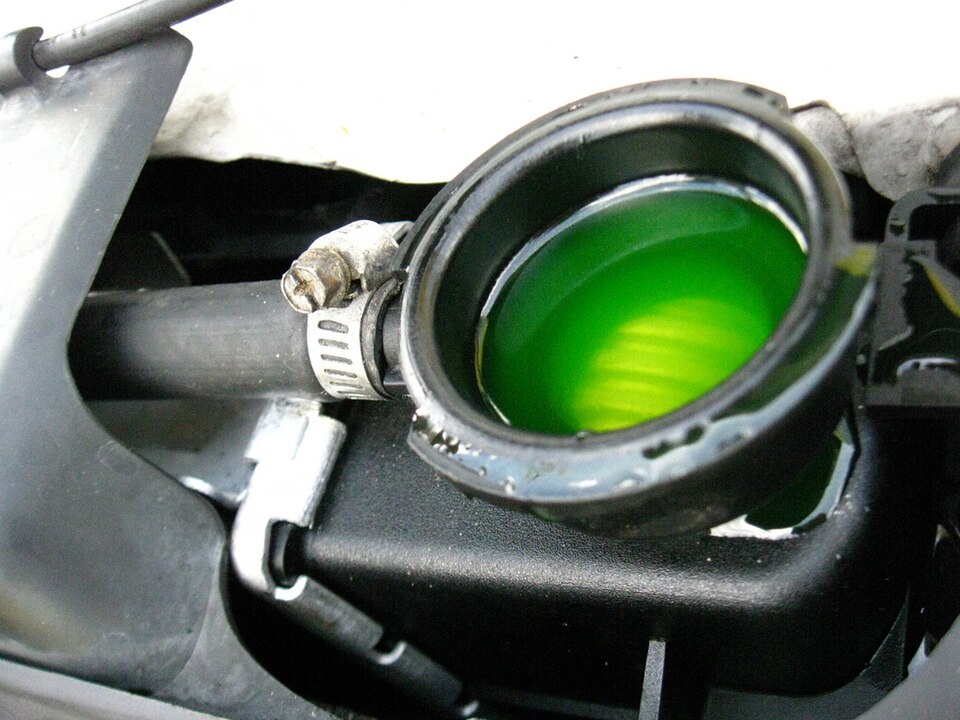 Lichid de răcire verde văzut prin gura de umplere a radiatorului, sub capota deschisă a unei mașini