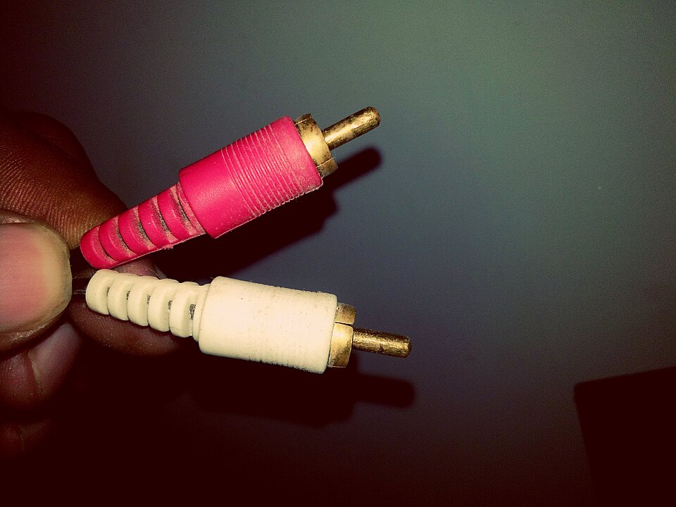 Două mufe RCA, una roșie și una albă, ținute între degete