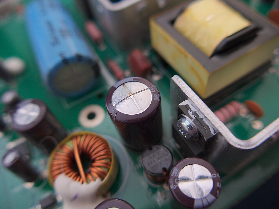 Condensator electrolitic cu capacul în cruce bombat, lângă alți condensatori, pe o placă dintr-un monitor LCD