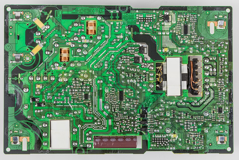Placa de alimentare a unui televizor LED, văzută pe partea lipiturilor, cu transformatorul, bobinele și condensatorul mare culcat